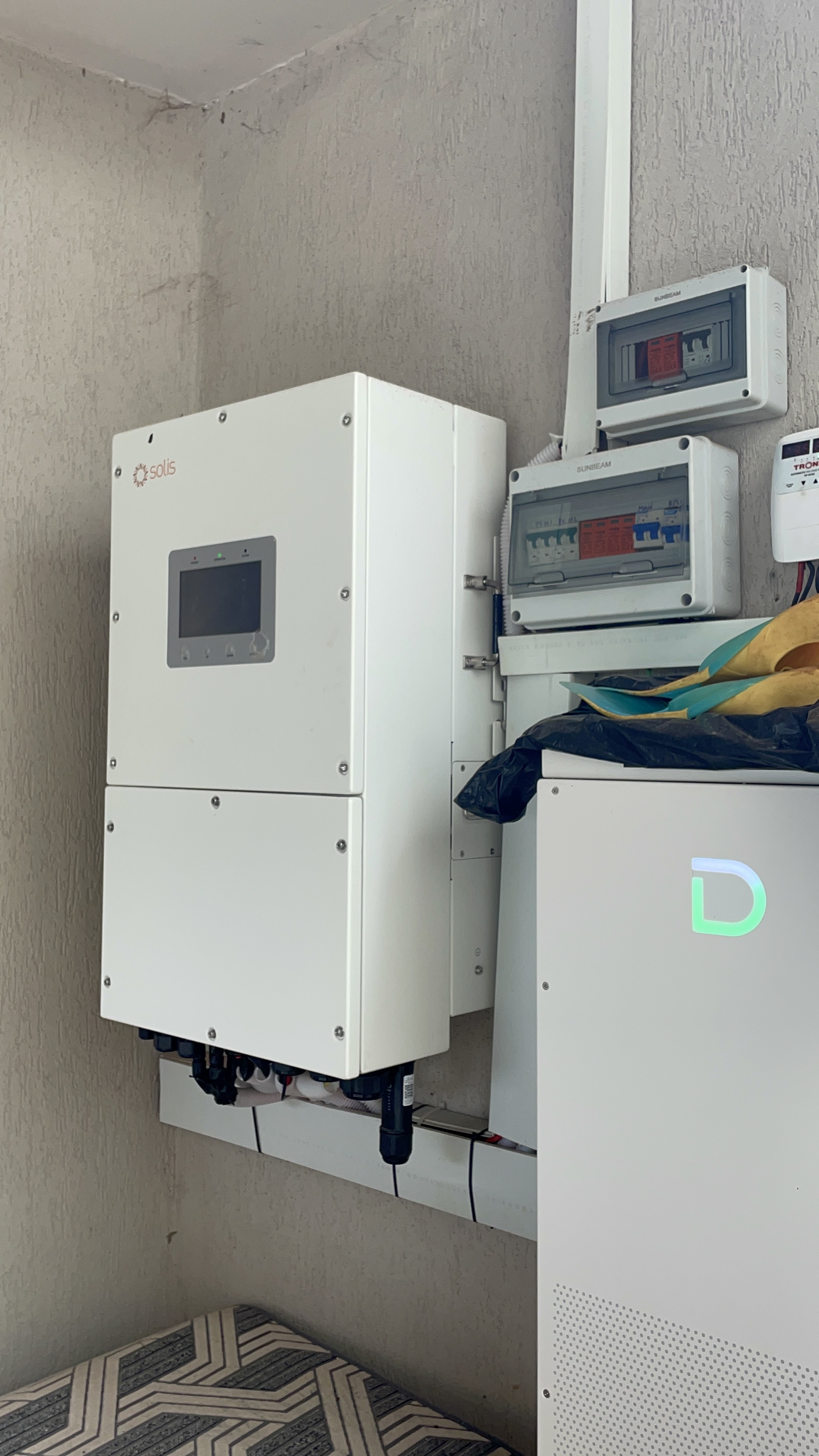 Solar inverter and electric distribution boxes mounted on textured exterior wall in service bay.